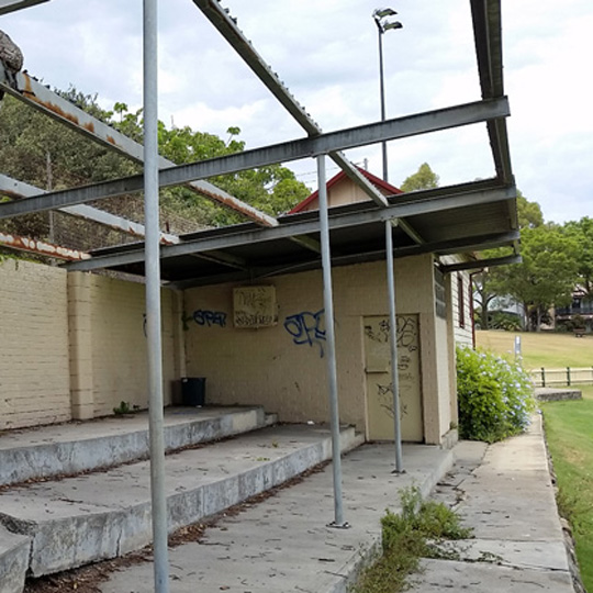Birchgrove Park eastern sports pavilion in its current state, with missing shade cover, no seats and cracks in the concrete floor.
